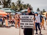 Com cartaz nas mãos e mais de 3 horas sob sol forte, Padre Arlindo faz peregrinação na praia pelo novo Instituto